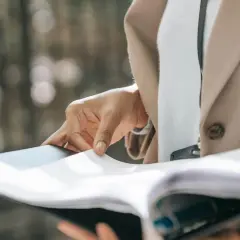 Dłoń przegląda dokumenty, przygotowując uruchomienie kredytu hipotecznego.