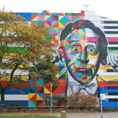 Kolorowe murale w Polsce: twarz mężczyzny z klawiszami fortepianu i geometrycznymi wzorami na fasadzie budynku.