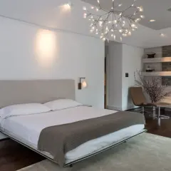 Camera da letto moderna con letto king-size, camino in pietra e un'elegante controsoffittatura che valorizza il design.