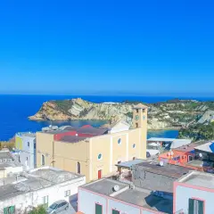 Vista panoramica dell'isola di Ponza con case colorate, una chiesa con campanile e il mare blu intenso.