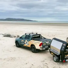 Un pick-up tracte un barbecue sur remorque sur une plage. Idéal pour fabriquer un barbecue sur remorque pour un événement en bord de mer.