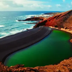 Zielona laguna otoczona czarną plażą i czerwonymi skałami. Niezwykłe miejsce, które warto zobaczyć na Lanzarote.