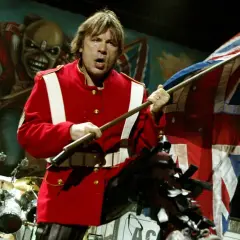 Bruce Dickinson z zespołu Iron Maiden na scenie z flagą Wielkiej Brytanii i Eddie'm w tle.
