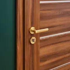Nowe drzwi na stare futryny Castorama, z drewnianym wykończeniem i złotą klamką, idealnie komponują się z zieloną ścianą.