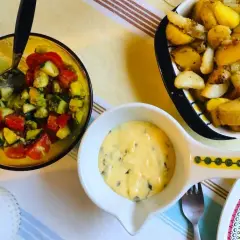 En skål med bearnaisesås recept, bredvid en sallad med tomat och gurka samt ugnsrostade potatisar.