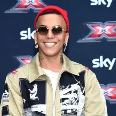 Artista con cappellino rosso e occhiali da sole, pronto a cantare le canzoni trap più famose.