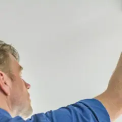 Mann montiert Rauchmelder an der Decke. In Bremen ist die Rauchmelderpflicht für Wohnungen gesetzlich vorgeschrieben.