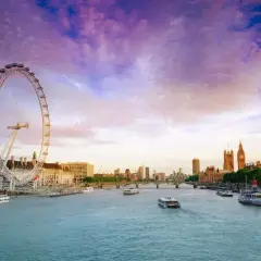 Zachód słońca nad Tamizą, z widokiem na London Eye i Parlament. Rzeka w Londynie lśni w purpurowym niebie.