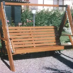 Un dondolo in legno fai da te, con seduta a doghe, è pronto per rilassarsi in giardino.