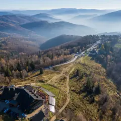 Widok z lotu ptaka na górskie krajobrazy i architekturę. Widać tu karczmę, parkingi i szlaki turystyczne, które są częścią równica atrakcje.