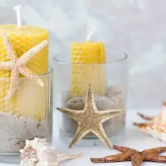 Candelabri fai da te con candele gialle, sabbia e stelle marine in bicchieri di vetro. Un tocco marino per la tua casa.
