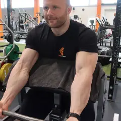 Mann im Fitnessstudio trainiert Bizeps mit Langhantel. Deutlich sichtbare Muskeln beim Bizeps dehnen.