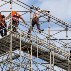 Szkolenie montaż rusztowań: pracownicy w kamizelkach i kaskach budują konstrukcję na wysokości.