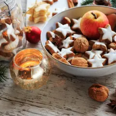 Weihnachtsplätzchen, Nüsse und ein Apfel in einer Schale, dazu eine Kerze – das ist die Bedeutung von Weihnachten: Gemütlichkeit und Genuss.