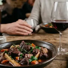 Un plat de gibier mijoté, servi avec un verre de vin rouge Cahors. Un repas réconfortant.