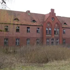 Opuszczony budynek z cegły, z charakterystycznymi okienkami na dachu, otoczony dziką roślinnością. Czy to najbardziej nawiedzone miejsce w Polsce?
