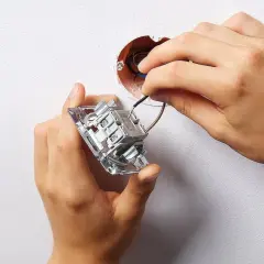 Ręce montują łącznik dwubiegunowy do ściany, podłączając przewody do mechanizmu.