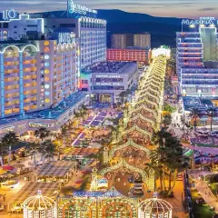 Noche vibrante en Marina d'Or, ciudad de vacaciones, con hoteles iluminados y un paseo lleno de luces y gente.