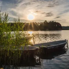 Dwa łodzie przy brzegu jeziora Świętajno, w blasku zachodzącego słońca.