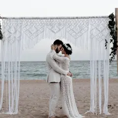 Para młoda przy bambusowej bramie z makramy na plaży. To piękny przykład, jak może wyglądać ślub humanistyczny co to.