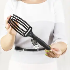 Kobieta trzyma czarną szczotkę do włosów Olivia Garden Fingerbrush.