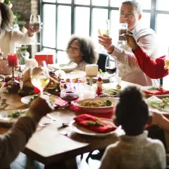 Familie feiert Weihnachten am festlich gedeckten Tisch. Alle stoßen an, die Stimmung ist fröhlich. Das ist die beste Weihnachtsrede!