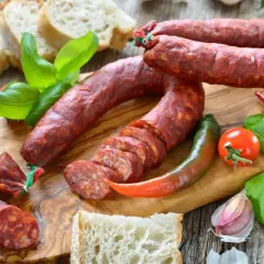 Chorizo co to? Pikantna kiełbasa, chleb, papryczki, pomidor i bazylia na desce.
