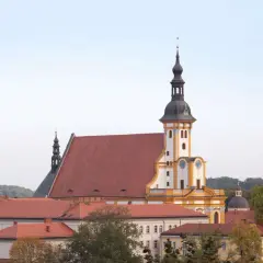 Das Kloster Neuzelle mit seinen roten Dächern und dem markanten Turm, umgeben von Bäumen.