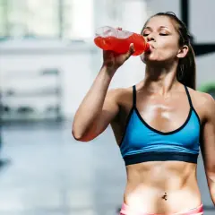 Eine Frau trinkt nach dem Training ein isotonisches Getränk. Es hilft, den Flüssigkeits- und Elektrolythaushalt auszugleichen.
