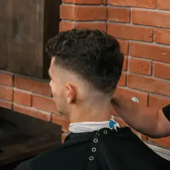 Mężczyzna z modną fryzurą fade, której nadano objętość za pomocą prestyler do włosów.