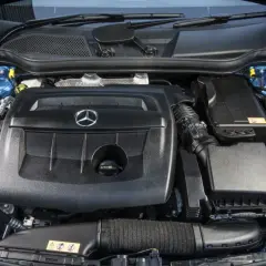 Motor de un Mercedes Clase A 180 gasolina, con su tapa negra y el logo de la estrella.