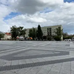 Dziecko śmiga gokartem po pustym, największym rynku w Polsce. W tle budynki i drzewa.