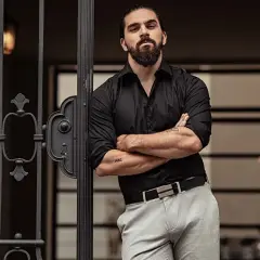 Elegancki mężczyzna w czarnej koszuli i jasnych spodniach. Czy jasny kolor pasuje do czarnego? Tak, tworzy stylowy kontrast.