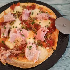 Pyszna pizza z tortilli na patelni, z szynką, oliwkami i serem. Idealna na szybki obiad.