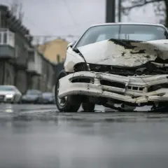Zniszczony biały samochód na ulicy. Po wypadku, czas pomyśleć, jak wyrejestrować samochód.