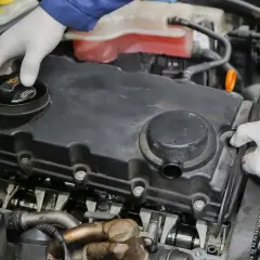 Mechanik w białych rękawiczkach sprawdza silnik. Może to być związane z nieszczelna odma objawy, które wymagają uwagi.