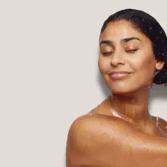 Frau mit geschlossenen Augen, die sich die nassen Haare wäscht. Sie genießt die Pflege, als würde sie ihre Haare nur mit Conditioner waschen.
