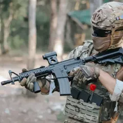 Jugador de fps airsoft con casco y rifle táctico, listo para la acción en un bosque.