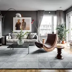 Stilvolles Wohnzimmer in Grau mit gemütlicher Couch, Design-Sessel und viel Grün. Tolle wohnzimmer grau ideen für ein modernes Zuhause.