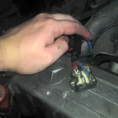 Ręka majstruje przy kostce elektrycznej, by sprawdzić wentylator nawiewu na krótko. Widoczny przekaźnik i przewody.