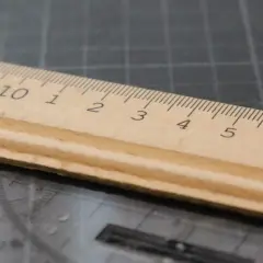 Une règle en bois sur un tapis de découpe, ses graduations formant une signature rythmique parfaite pour mesurer.