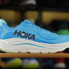Niebieskie buty sportowe Hoka z charakterystycznym logo. To firma znana z innowacyjnych rozwiązań w obuwiu biegowym.