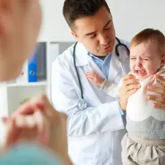 Lekarz uspokaja płaczące dziecko, które przechodzi skok rozwojowy. Jak sobie radzić z trudnymi emocjami malucha?