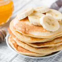 Pancake perfetti, dorati e soffici, preparati con la friggitrice ad aria, guarniti con fette di banana e miele.
