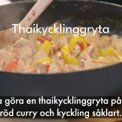 En thaikycklinggryta med kycklingbitar, gul och röd paprika i en krämig sås i en stekpanna.