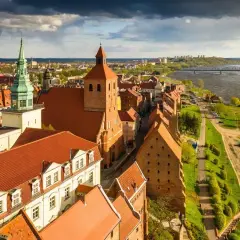 Widok na zabytki w Polsce: ceglane kamienice, kościół z zieloną wieżą i Wisła.
