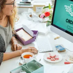 Dwie kobiety przeglądają komputer, na ekranie widnieje napis "ORDER" i ikona ciężarówki. To pokazuje, jak działa preorder.