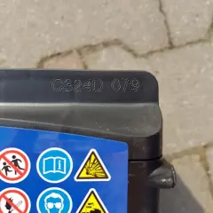 Na akumulatorze Exide widoczny kod C324D 079, który może oznaczać datę produkcji. Obok symbole ostrzegawcze.