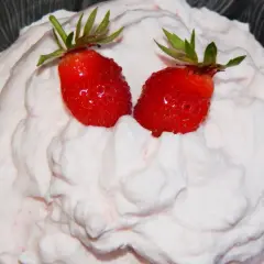 Puszysty krem z mascarpone i białej czekolady, ozdobiony dwoma soczystymi truskawkami.