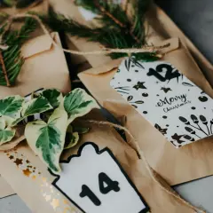 Sacchetti marroni per realizzare calendario dell'avvento fai da te, decorati con pigne, foglie e numeri.